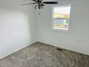 Carpeted spare room featuring a ceiling fan and baseboards