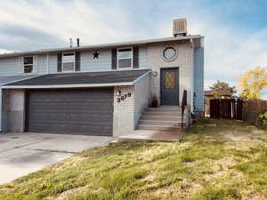 Split foyer home featuring concrete driveway, a garage, entry steps, and brick siding