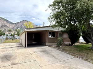 View of front of property with concrete driveway, a mountain view, and an attached carport
