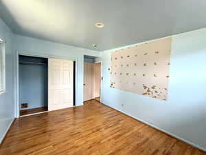 Unfurnished bedroom with wood finished floors and a closet