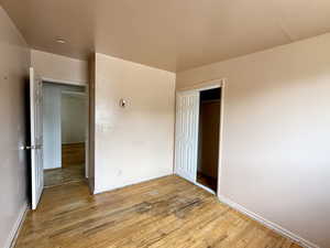 Unfurnished bedroom with wood finished floors and a closet