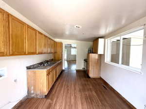Kitchen featuring dark wood-style flooring, brown cabinetry, and stainless steel microwave