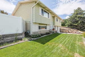 Back of house with a yard and brick siding