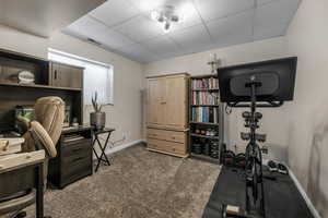 Office area with a drop ceiling and carpet flooring