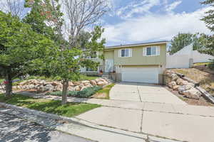 Bi-level home with brick siding, a garage, and concrete driveway