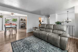 Living area featuring a chandelier, wood finished floors, ceiling fan, and a textured ceiling