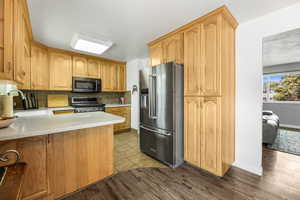 Kitchen featuring appliances with stainless steel finishes, tasteful backsplash, light wood-type flooring, a peninsula, and light stone counters