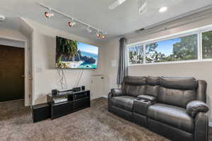Carpeted living room featuring track lighting, a textured ceiling, and ceiling fan