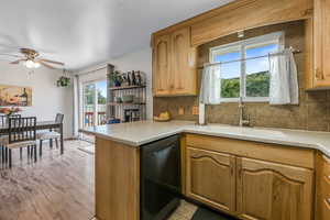 Kitchen featuring dishwashing machine, tasteful backsplash, a ceiling fan, and a peninsula