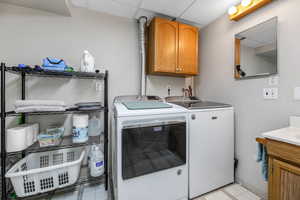 Washroom with cabinet space, washing machine and clothes dryer, and light tile patterned floors
