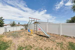 Fenced backyard featuring a playground