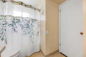 Bathroom featuring toilet and a shower with curtain