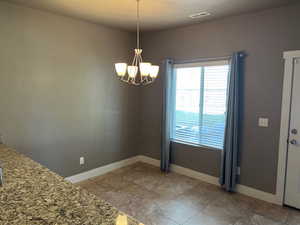 Unfurnished dining area featuring a chandelier and plenty of natural light