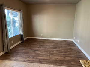 Empty room with dark wood-style flooring and baseboards