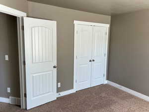 Unfurnished bedroom with carpet, a closet, and a textured ceiling