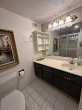 Bathroom with vanity, a shower stall, tile patterned flooring, and a textured ceiling