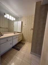 Bathroom with wallpapered walls, vanity, a textured ceiling, and tile patterned floors