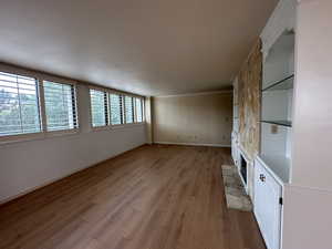 Unfurnished living room with light wood finished floors, ornamental molding, and a fireplace
