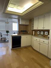 Kitchen with dishwasher, light wood-style floors, open shelves, and a chandelier