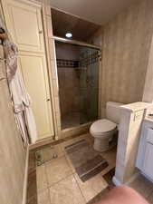 Bathroom with wallpapered walls, a shower stall, tile patterned flooring, vanity, and recessed lighting