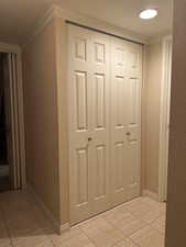 Hallway with crown molding and light tile patterned floors