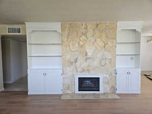 Unfurnished living room featuring wood finished floors and a stone fireplace