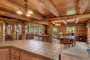Dining space featuring rustic walls, a wooden ceiling with exposed beams, an large breakfast bar