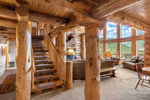 Staircase featuring large rustic beams, wood stairs, wood ceiling with exposed beams