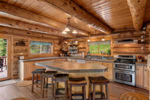 Kitchen featuring double oven range, healthy amount of natural light, tile counters, a wood ceiling with exposed beams, and log walls