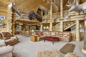 Large living area with a towering ceiling, log walls, and wooden ceiling