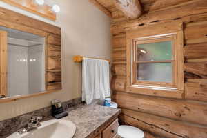 Bathroom #1 featuring log walls, a wooden ceiling with exposed beams, a shower, and vanity