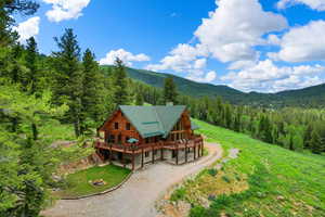 Aerial view of property and surrounding area featuring a heavily wooded area and mountains