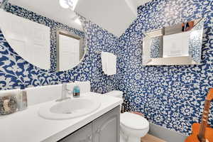 Bathroom with wallpapered walls, vanity, and a shower with curtain