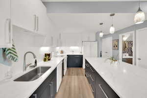 Kitchen featuring white appliances, white cabinetry, dark cabinetry, light wood-style flooring, and backsplash