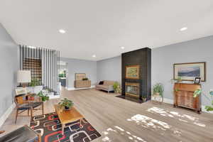 Living room featuring wood finished floors, a fireplace, and recessed lighting