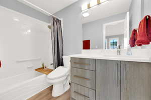 Full bath featuring vanity, shower / bath combination with curtain, and wood finished floors