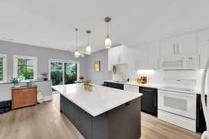 Kitchen with white appliances, light countertops, light wood-style floors, and white cabinets