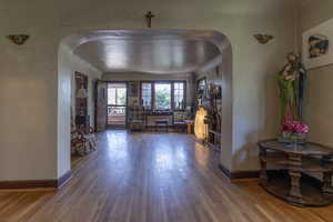 Entryway featuring arched walkways and wood finished floors