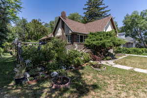 View of property exterior with a chimney, a lawn, a shingled roof, and brick siding