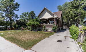 View of front of property with a front yard, brick siding, a porch, and a roof with shingles