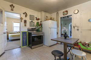 Kitchen with freestanding refrigerator, stainless steel electric range, and light floors
