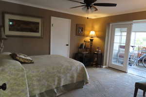 Bedroom with light colored carpet, ornamental molding, ceiling fan, and access to exterior