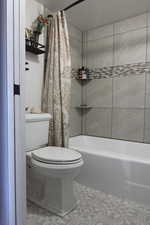 Bathroom featuring toilet and shower / tub combo with curtain