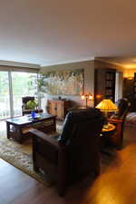 Living room with wood-type flooring and crown molding
