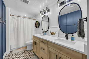 Basement bathroom with a double vanity, quartz countertops, shower / bathtub combo, and tile flooring
