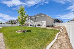 Rear view of property featuring a fenced backyard, stucco siding, and stairs
