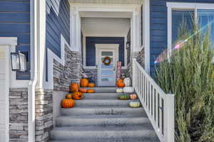 View of exterior entry with stone siding and a porch