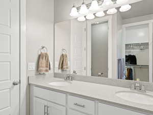 Full bathroom featuring double vanity and a spacious closet