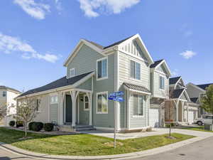 View of front of home with board and batten siding, an attached garage, concrete driveway, a front yard, and stone siding