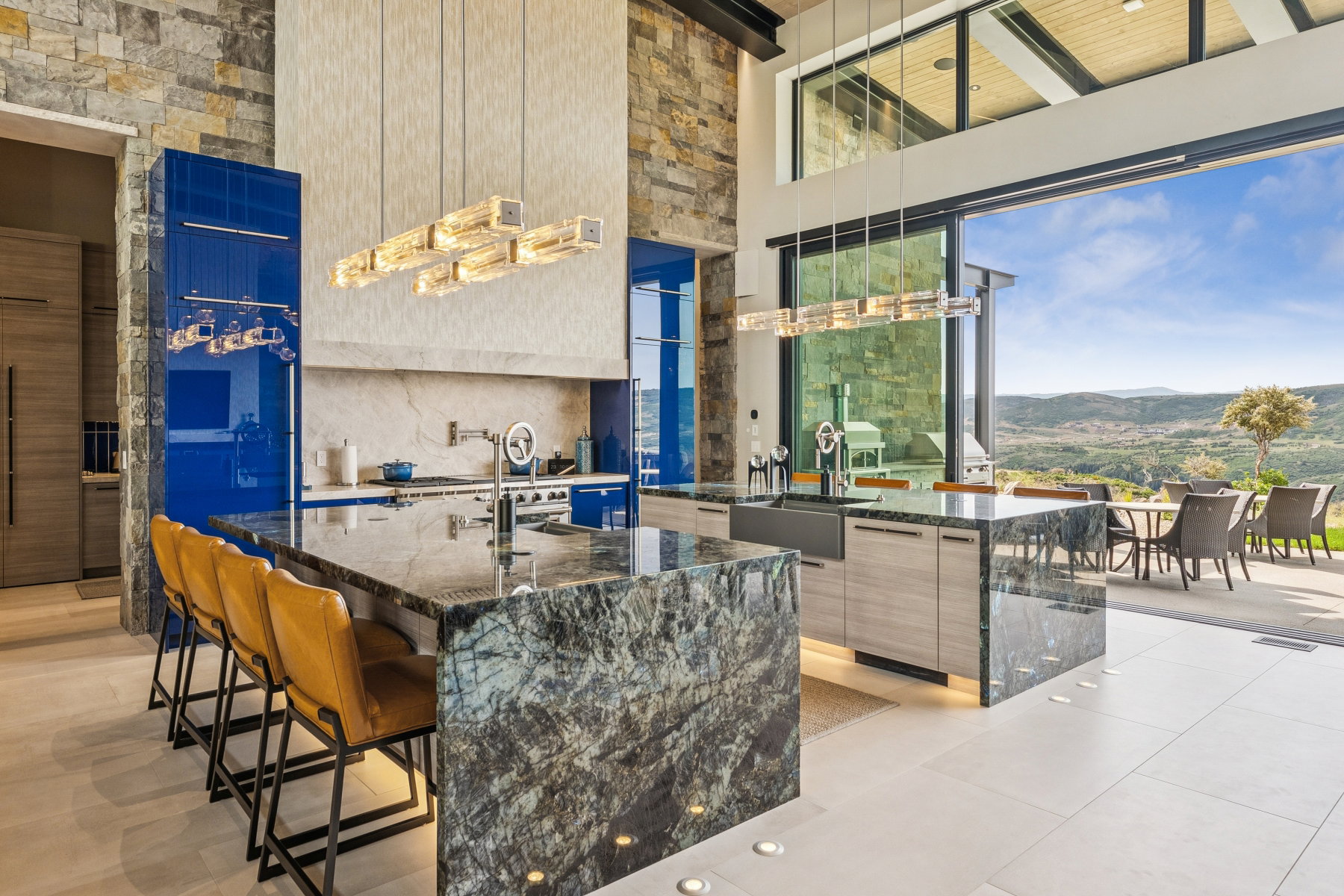 Kitchen with modern cabinets, a towering ceiling, a mountain view, dark stone counters, and a kitchen island with sink